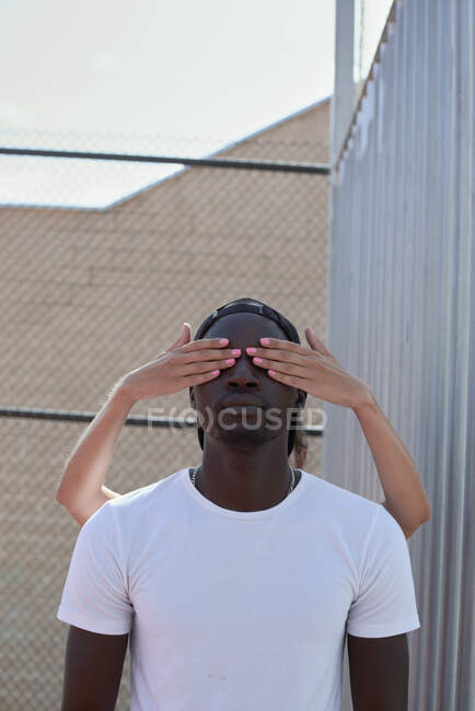 The hands of a white woman cover the eyes of a black man — Stock Photo