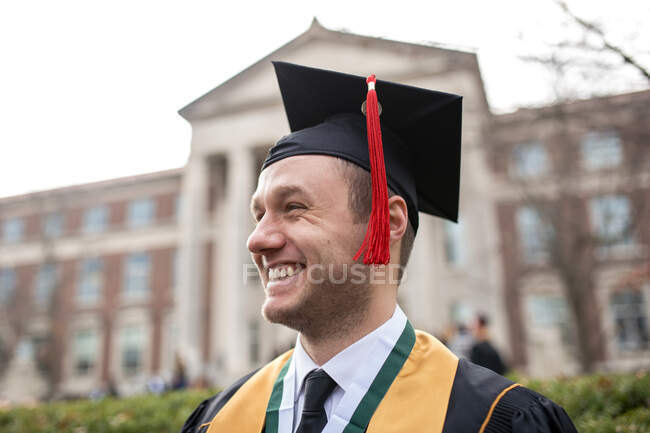 Retrato de jovem orgulhoso em boné de graduação e vestido — Fotografia de Stock