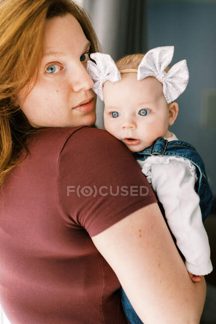 Маленька дівчинка в обіймах своєї матері дивиться з несподіванкою — стокове фото