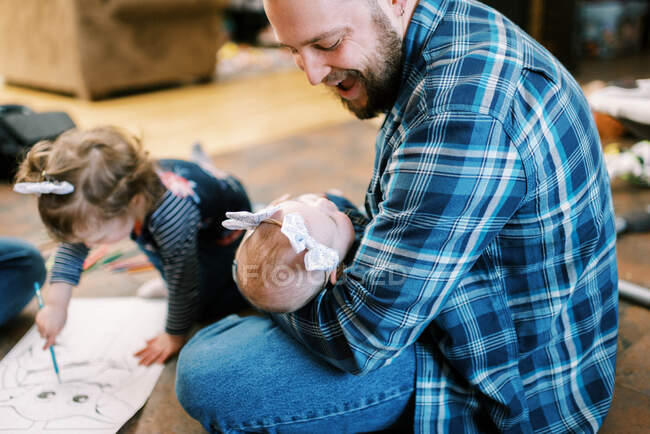 Um jovem pai alegre fazendo rostos em sua filha bebê — Fotografia de Stock