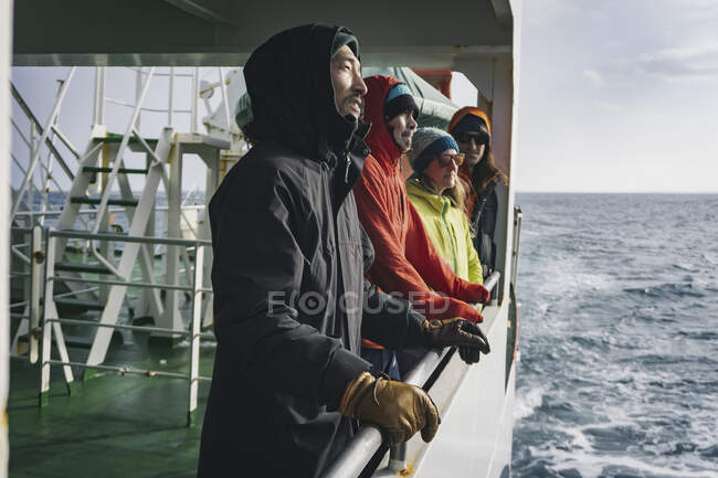 People in warm clothing looking at view while traveling in boat on river during vacation — Stock Photo