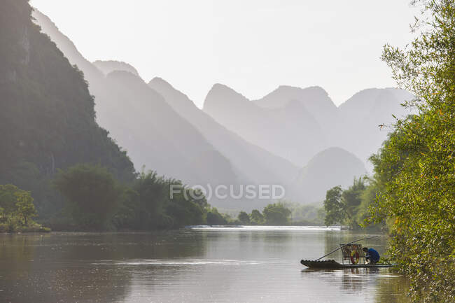 Pêcheur sur un radeau traditionnel sur la rivière Yulong près de Yangshuo — Photo de stock