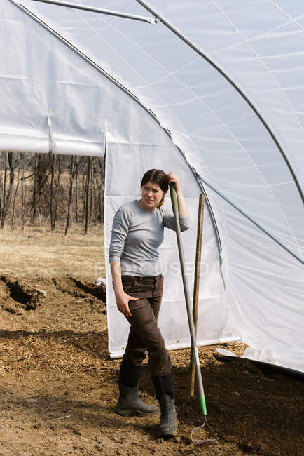 Uma jovem agricultora trabalhando em casa verde pela manhã na primavera — Fotografia de Stock