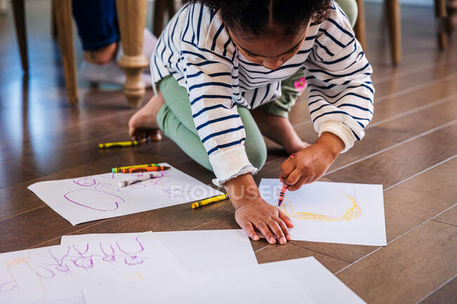 Девушка рисует мелками на бумаге дома — стоковое фото