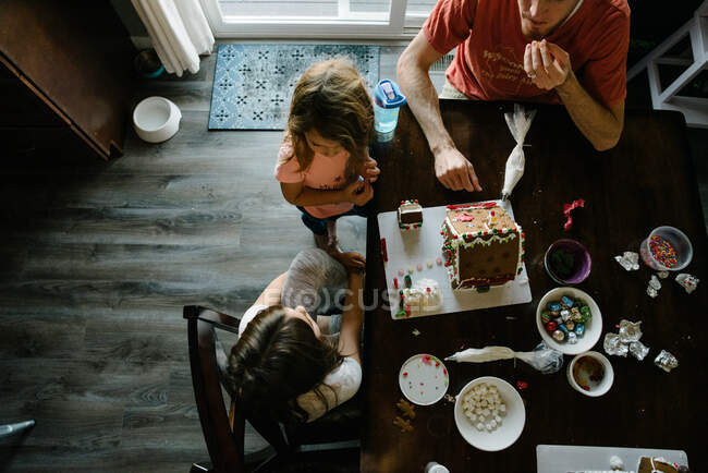 Familie bastelt gemeinsam Lebkuchenhäuser zu Hause — Stockfoto