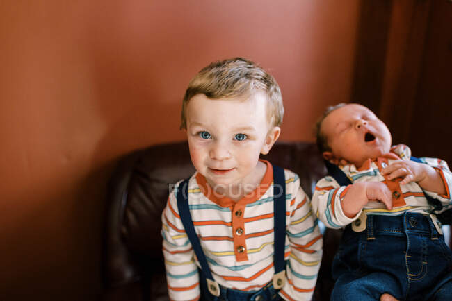 Un niño pequeño y su hermano recién nacido codo con codo - foto de stock