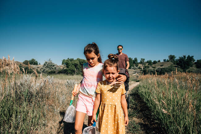 Старшая сестра утешает младшую сестру, когда она плачет на прогулке на природе — стоковое фото