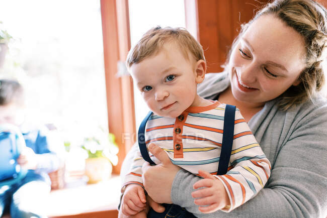 Une mère tenant son petit garçon dans ses bras dans sa maison — Photo de stock