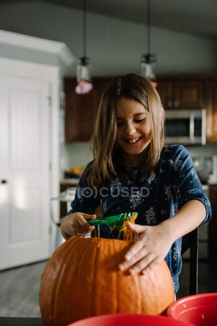 Chica sacando semillas de calabaza de una calabaza en Halloween - foto de stock