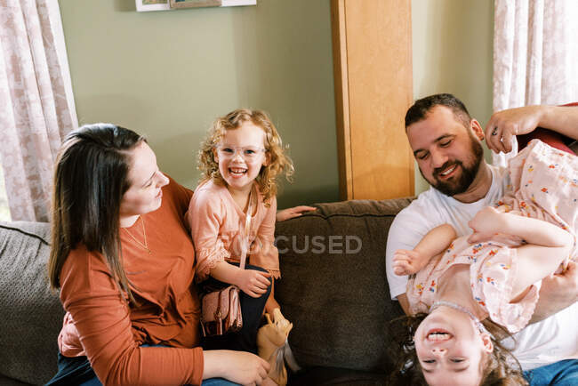 Familia con dos chicas riendo juntas en la sala de estar - foto de stock