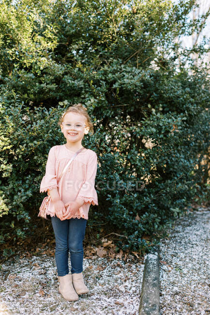 Маленька мила дівчинка посміхається великий стоячи у своєму дворі з блискучою сумочкою — стокове фото