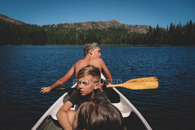 Trois garçons partent en voyage dans un petit canot — Photo de stock