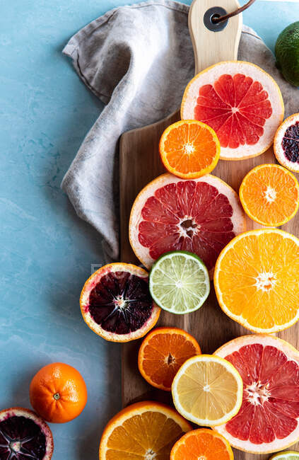 Грейпфруты и ломтики апельсинов на деревянной доске, вид сверху. — стоковое фото