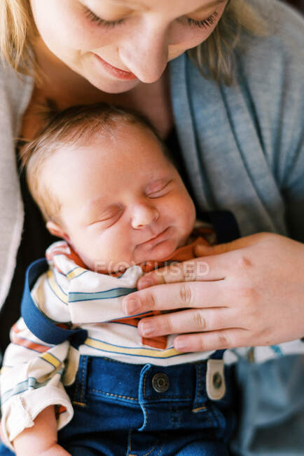 Une jeune mère tenant son nouveau-né paie avec amour et souriant ensemble — Photo de stock