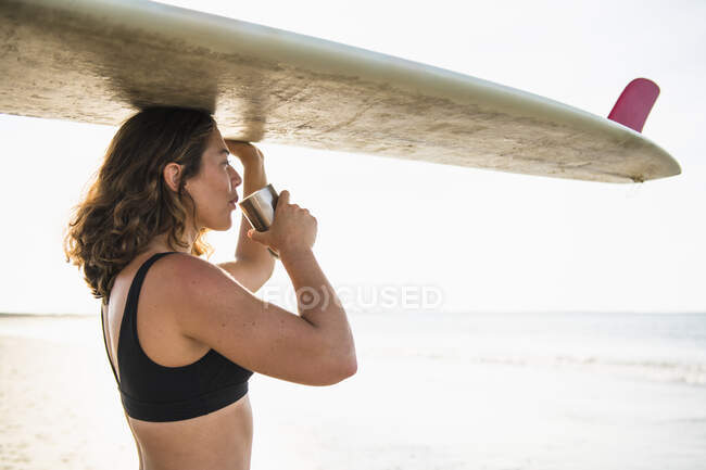 Surfista mulher com bordo beber café na praia — Fotografia de Stock