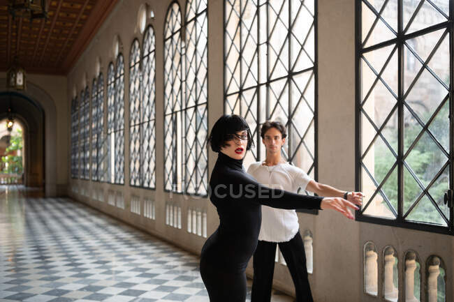 Energetic female dancer spinning around during Latin dance with male partner in hallway — Stock Photo