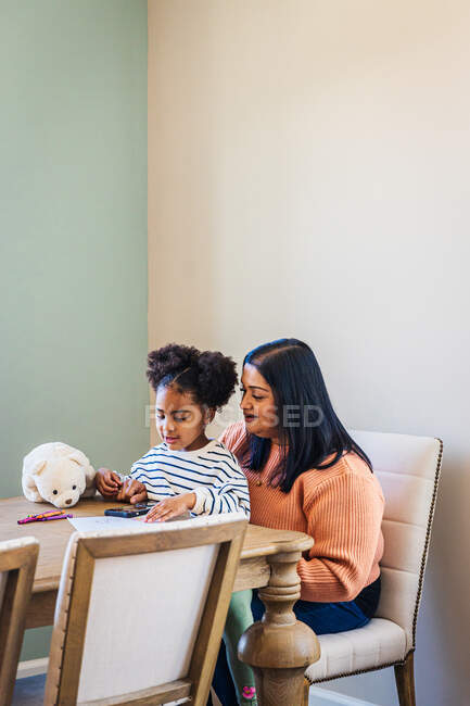 Petite-fille et grand-mère utilisant un smartphone à la maison — Photo de stock