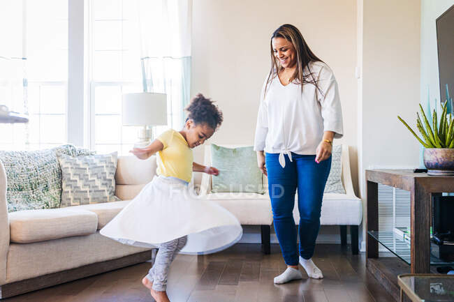 Lächelnde Mutter schaut Tochter beim Tanzen im heimischen Wohnzimmer an — Stockfoto