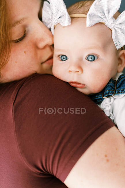 Una niña en brazos de su madre mirando con sorpresa - foto de stock