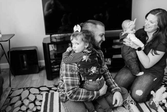 Uma jovem família feliz com um bebê brincando juntos na sala de estar — Fotografia de Stock