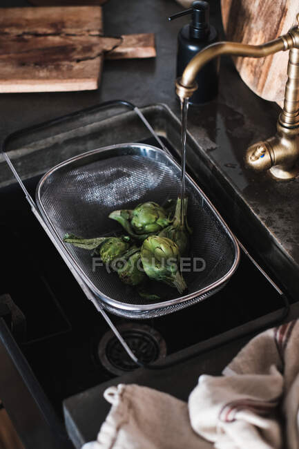 Fresh artichokes vegetables and tap on a wooden table — Stock Photo