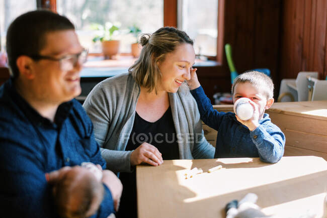 Una giovane famiglia seduta accanto al tavolo da pranzo con neonato e bambino — Foto stock