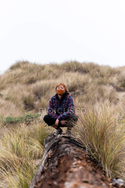 Adolescente con maschera seduta su tronchi di sabbia costiera duna il giorno nebbioso — Foto stock