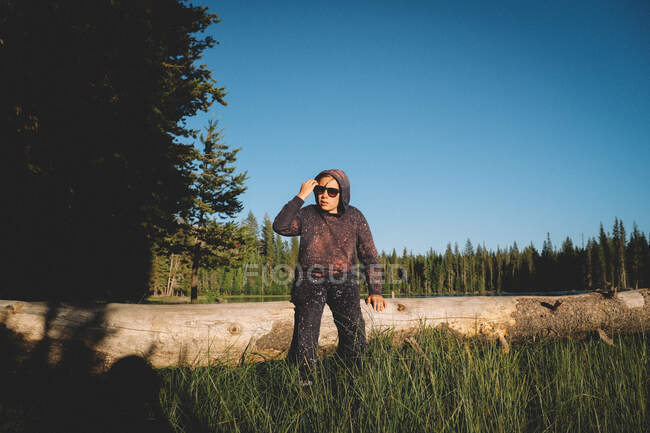 Young man in a hat and a jacket with a backpack on the background of the forest — Stock Photo
