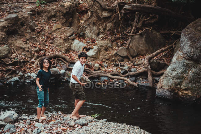 Frères et sœurs qui s'amusent sur les rives d'une rivière — Photo de stock