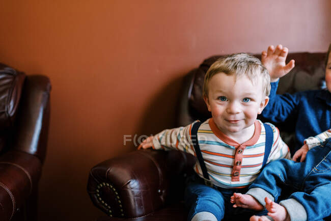 Piccolo bambino seduto accanto ai suoi fratelli su una poltrona sorridente — Foto stock