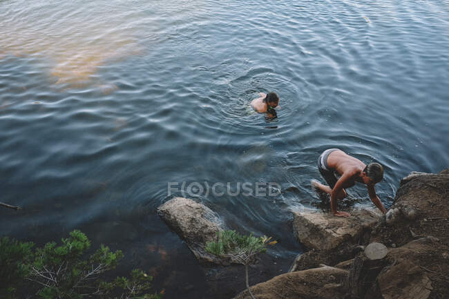 Dois meninos rastejam para a costa de um lago de montanha — Fotografia de Stock