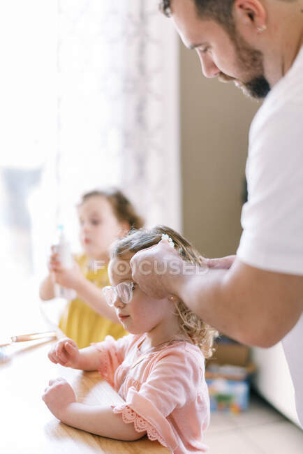 Un padre che si prende cura delle sue figlie e acconciatura i capelli per la scuola — Foto stock