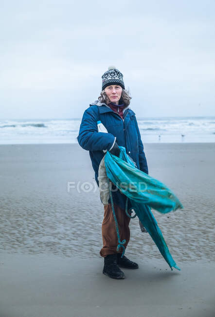 Donna matura sulla cinquantina che pulisce la spiaggia in una giornata ventosa in Danimarca — Foto stock