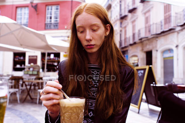 Giovane donna dai capelli rossi che beve caffè sulla terrazza di un bar — Foto stock