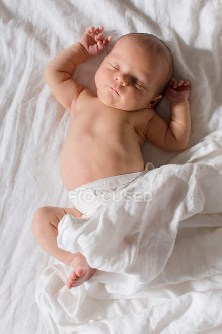 Newborn baby sleeping on white bed with white sheets — Stock Photo