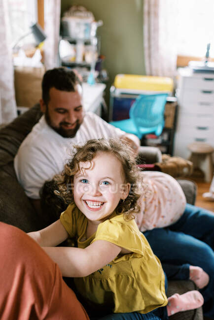 Joven chica feliz riendo mientras juega con los padres y hermanos - foto de stock