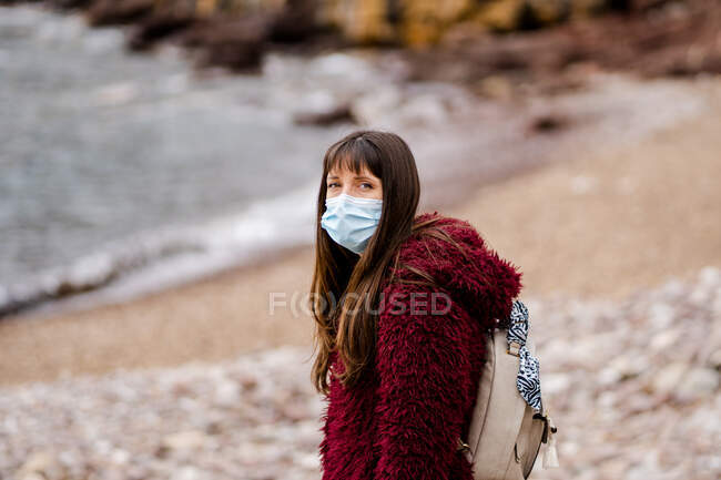 Mulher branca jovem na praia no inverno com máscara facial — Fotografia de Stock