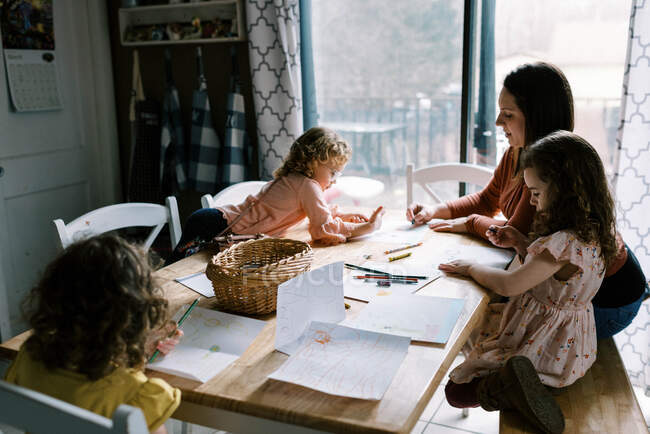 Uma mãe amorosa e seus filhos pequenos colorir juntos e ligação — Fotografia de Stock