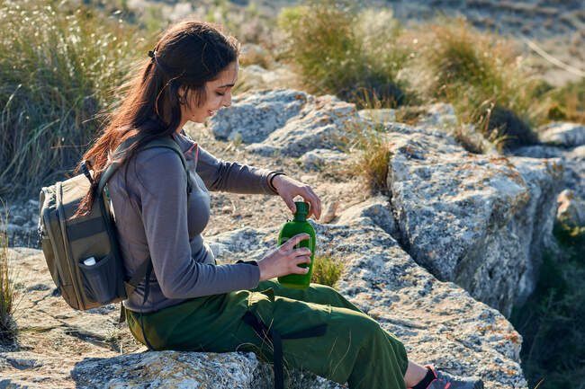 Mulher exploradora água potável de uma cantina no topo de uma montanha — Fotografia de Stock