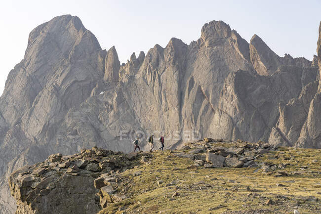 Male and female backpackers walking by rocky cliff during vacation — Stock Photo