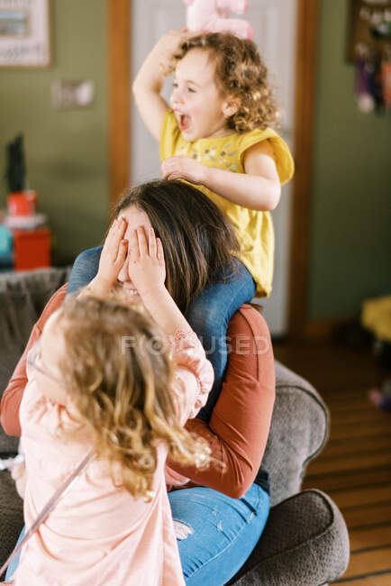 Une jeune mère jouant sauvagement avec ses enfants dans le salon — Photo de stock