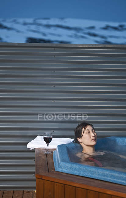 Femme se relaxant dans un bain à remous à l'extérieur du chalet en Islande — Photo de stock