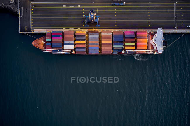 Vista drone superiore della nave da carico caricata con container multicolore ormeggiati al molo in porto — Foto stock
