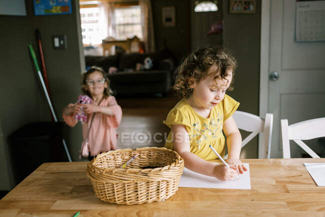 Twin toddler girls spending time together in kitchen while coloring — Stock Photo