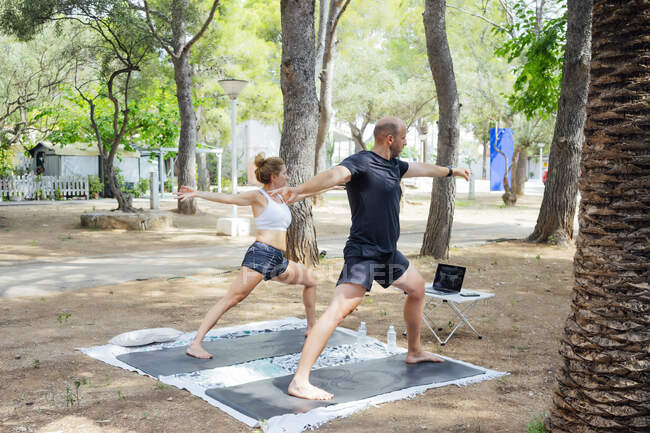 Glückliches Paar beim Yoga im Wald. Sie treiben Sport im Freien. Gesunder Lebensstil. Kopierraum. — Stockfoto