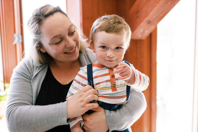 A mother holding her little toddler boy in her arms in her home — Stock Photo