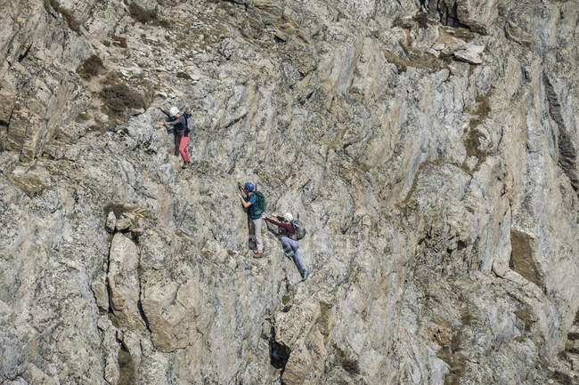 Vista de ángulo alto de excursionistas masculinos y femeninos escalando acantilado rocoso - foto de stock