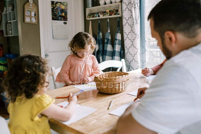 Petites filles et leur père colorier ensemble à la table de cuisine — Photo de stock
