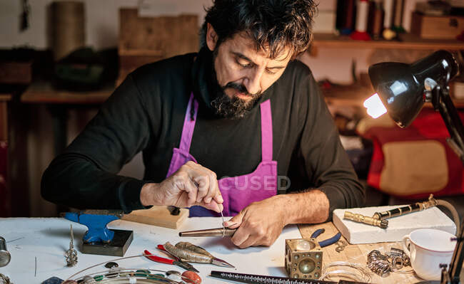 Jeweler craftsman working at work table inside workshop — Stock Photo