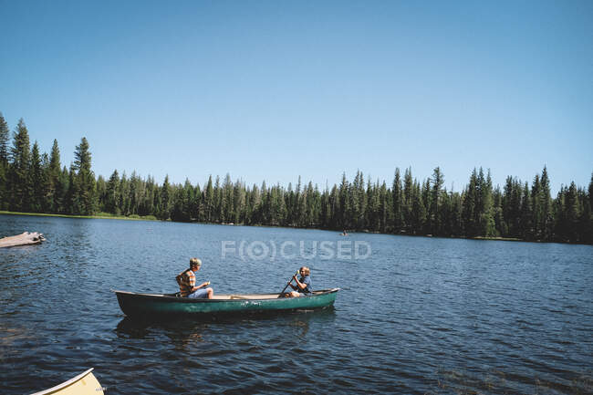 Deux garçons s'aventurent sur le lac Rucker dans un canot vert — Photo de stock